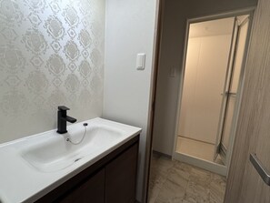 A bathroom with a white sink, black faucet, and patterned wallpaper. - Beach side Pension mibal (Nanjo)