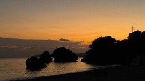 A coastal sunset with rock formations silhouetted against the sky. - Beach side Pension mibal (Nanjo)