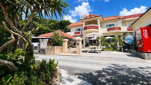 A hotel with a red-tiled roof, outdoor seating, and a Coca-Cola vending machine. - Beach side Pension mibal (Nanjo)
