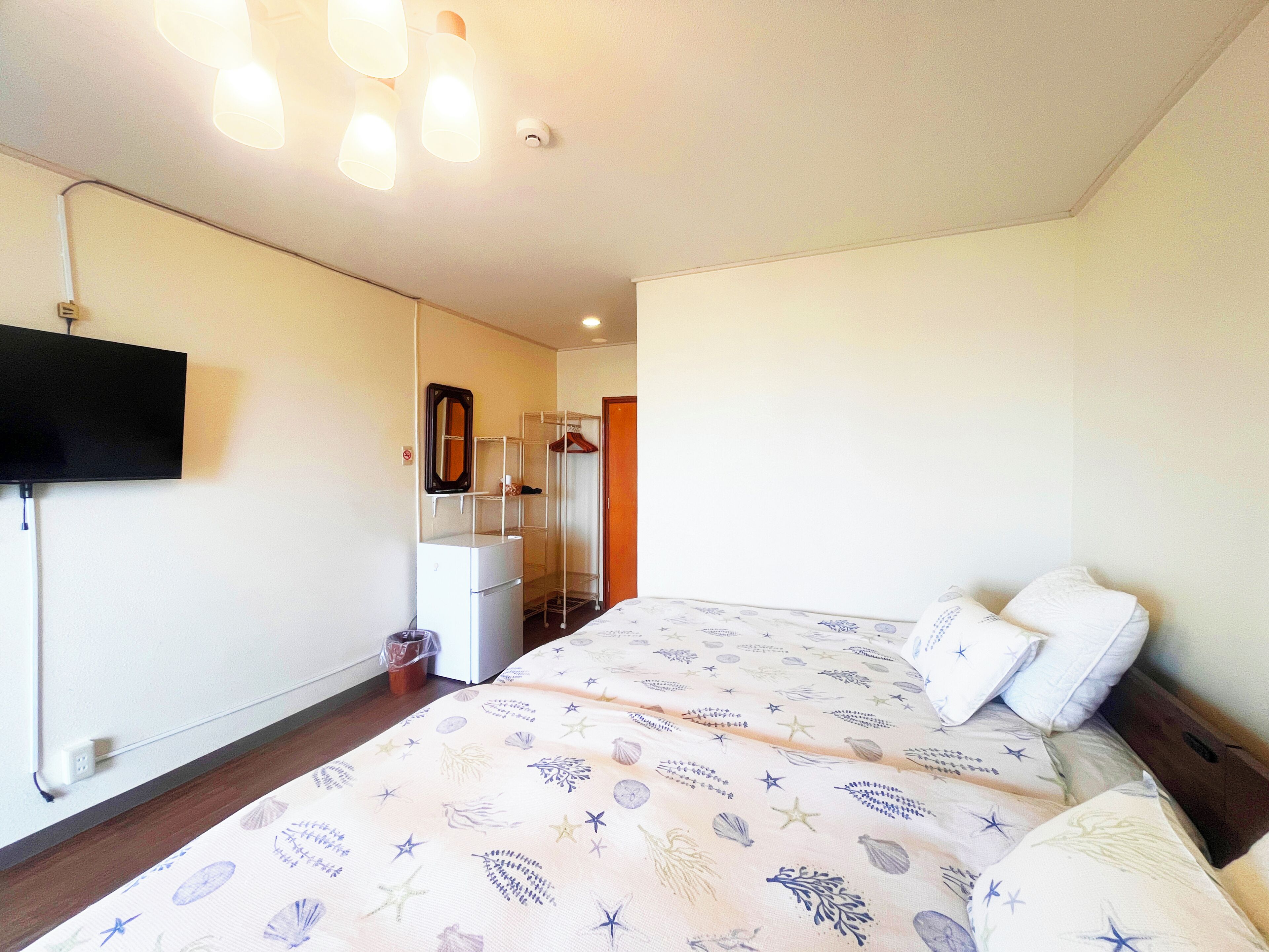 A hotel room with a bed, a television mounted on the wall, a wardrobe, and a mirror.