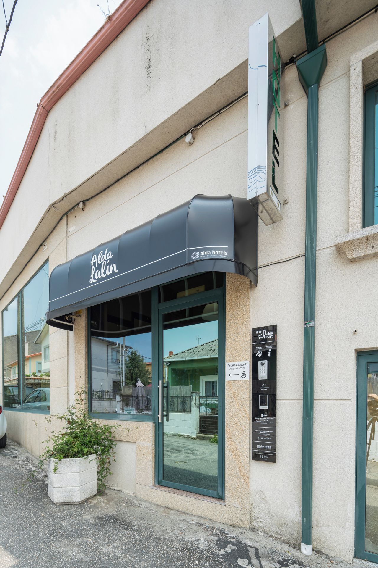 A hotel with a black awning, large windows, and a sign indicating accessibility features.