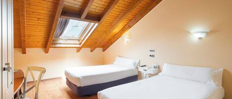 A bedroom with two beds, a wooden ceiling, and a skylight.