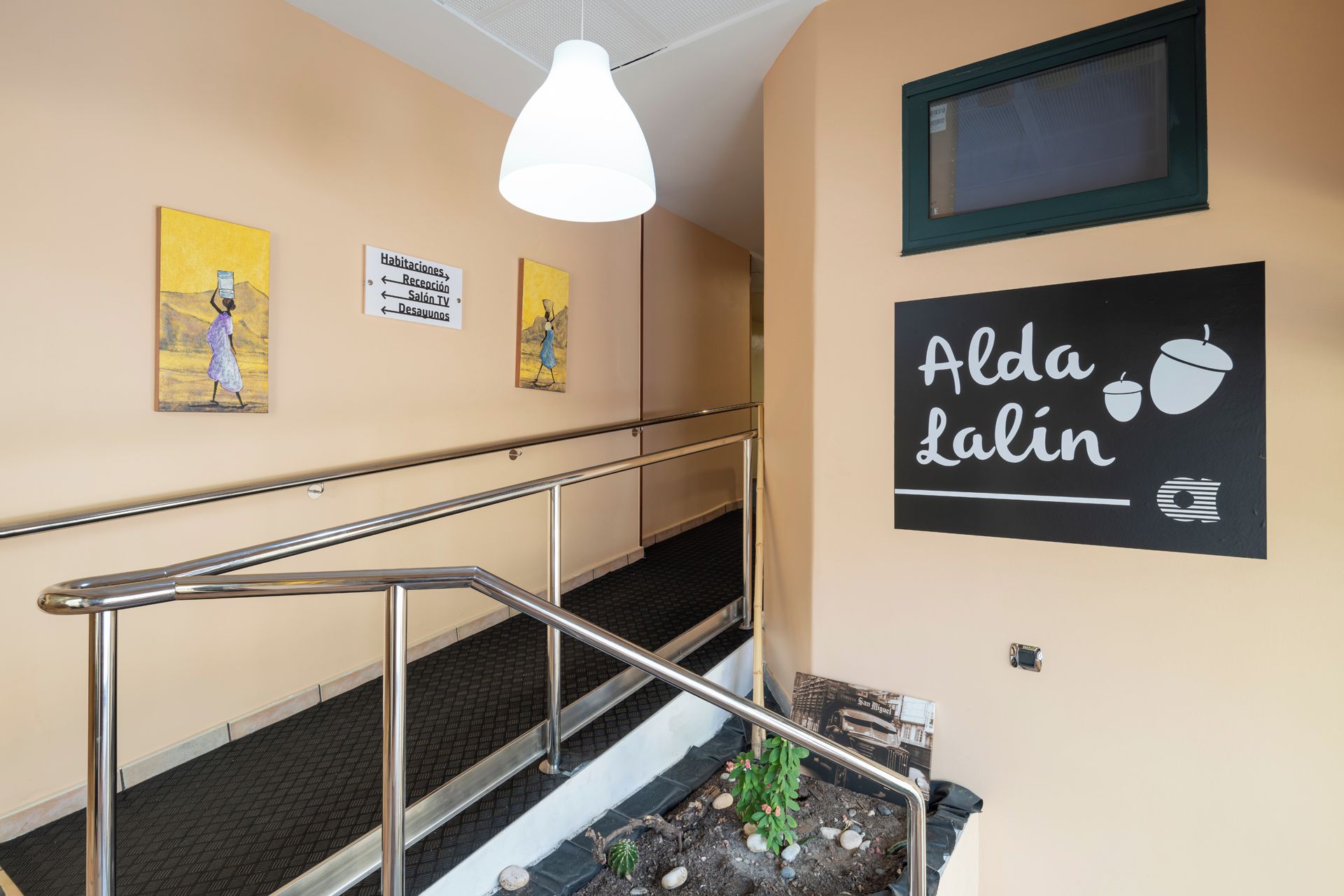 Interior de hotel con escalera, indicaciones y obras de arte.