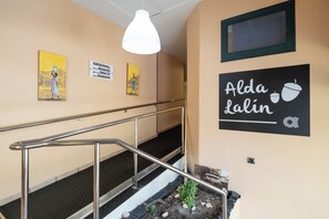 A hotel interior with a staircase, directional signs, and artwork. - Alda Lalín (Lalin)