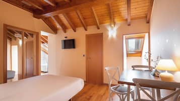Un dormitorio con techo de madera, una cama, un televisor y una ventana con cortinas.