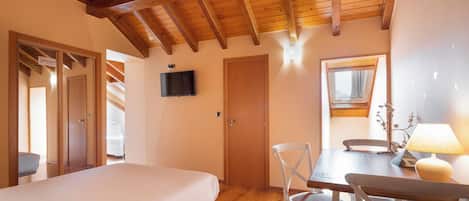 A bedroom with a wooden ceiling, a bed, a TV, and a window with curtains.