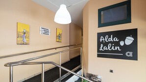 A hotel interior with a staircase, directional signs, and artwork. - Alda Lalín (Lalin)