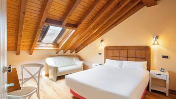 A bedroom with a wooden ceiling, a bed, a chair, and bedside tables.