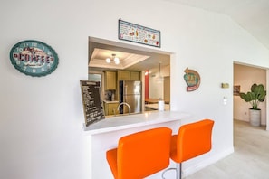 A modern kitchen with a bar area, a clock, and a menu board. - 70s Villa! Heated Pool+Spa, Basketball, Pickleball - Holiday Home (Las Vegas)