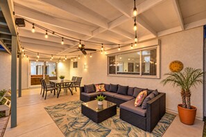 An outdoor patio area with a dining table, sofa, and ceiling fans.