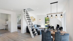 A modern interior with a staircase, dining area, and a view of the outdoors.
