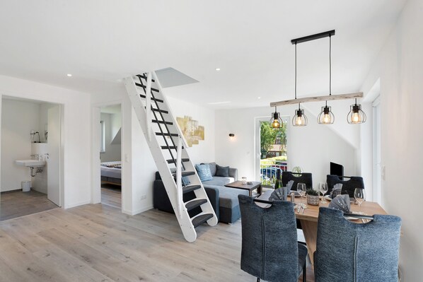 Un interior moderno con una escalera, comedor y vistas al exterior.