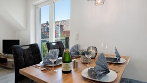 A dining table set with plates, cutlery, glasses, and a bottle of champagne.