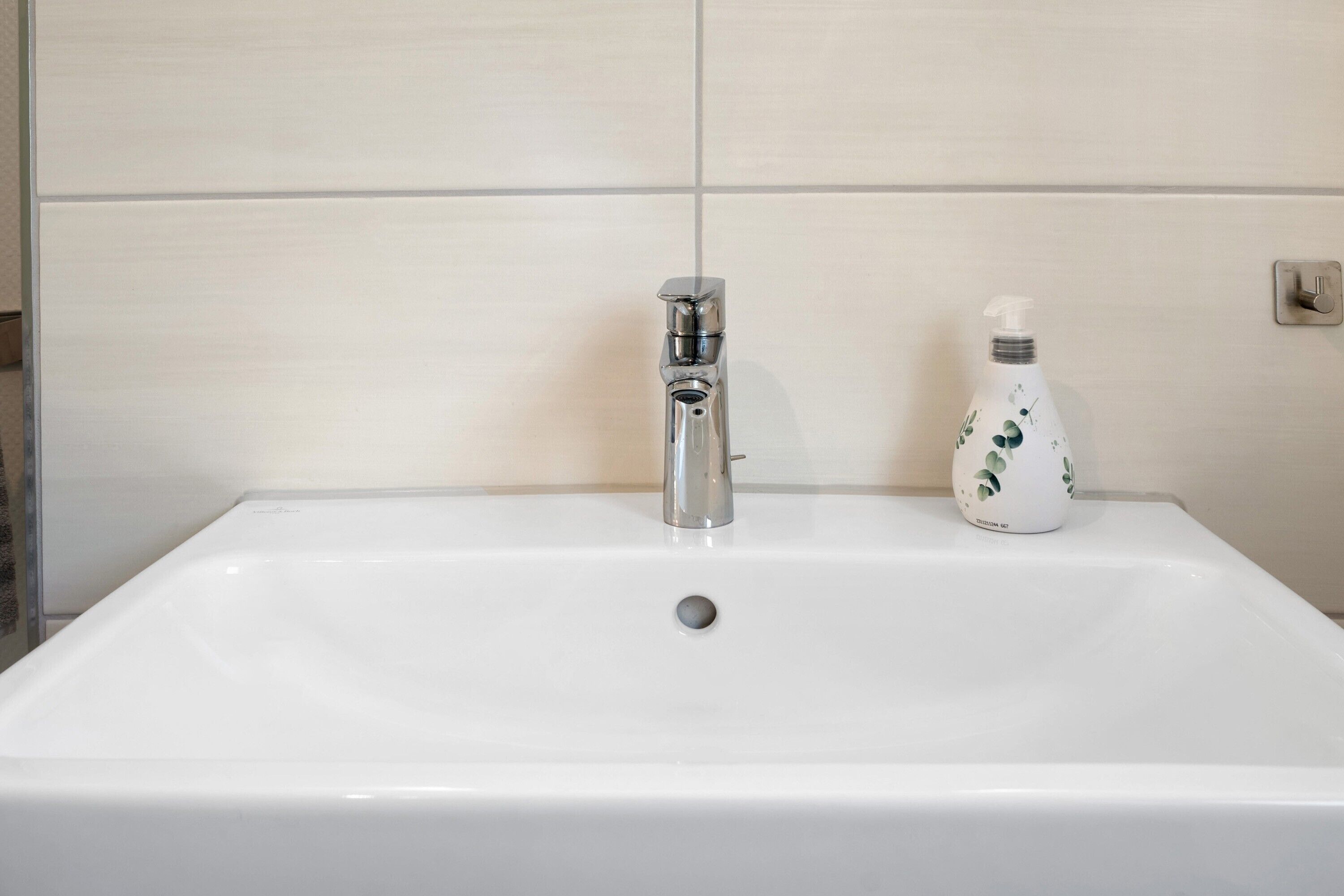 Une salle de bain avec un lavabo blanc, un robinet et un distributeur de savon.