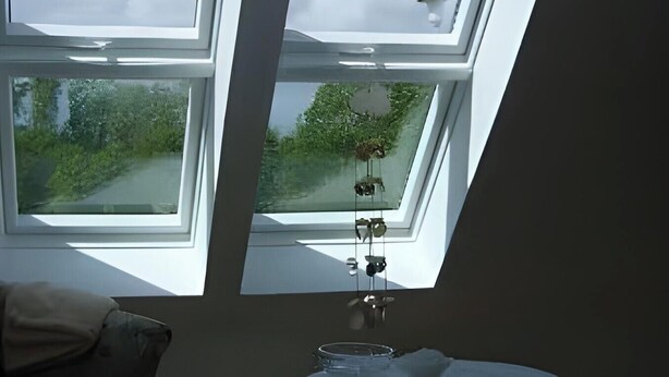 Ein Zimmer mit Oberlichtern, einem Tisch mit weißer Tischdecke und einem Stuhl.