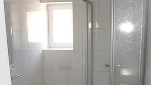 Ett badrum med dusch, toalett, handfat och ett fönster.