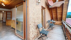 Une terrasse en bois avec une porte vitrée donnant sur une pièce, une antenne parabolique et une vue sur l’extérieur.