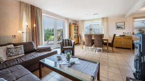 A living room with a sofa, coffee table, and dining area with chairs and a table. - Sustainable Holiday Apartment "Lichtblick" with Private Terrace, Garden, Wi-Fi & EV Charger (Grömitz)