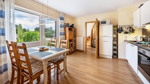 Une cuisine moderne avec des meubles en bois, un coin repas comprenant une table et des chaises, et une vue par la fenêtre.