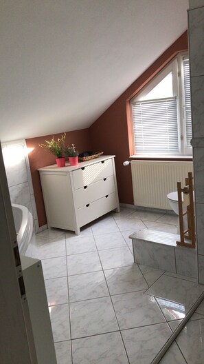 A small, well-lit bathroom with a white vanity, a radiator, and a window with blinds. - Apartment 'Ferienwohnung Mandelblüte' with Mountain View and Wi-Fi (Schotten)