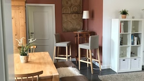 A dining area with a wooden table and chairs, a bench, a white bookshelf, and a wall with a circular pattern. - Apartment 'Ferienwohnung Mandelblüte' with Mountain View and Wi-Fi (Schotten)