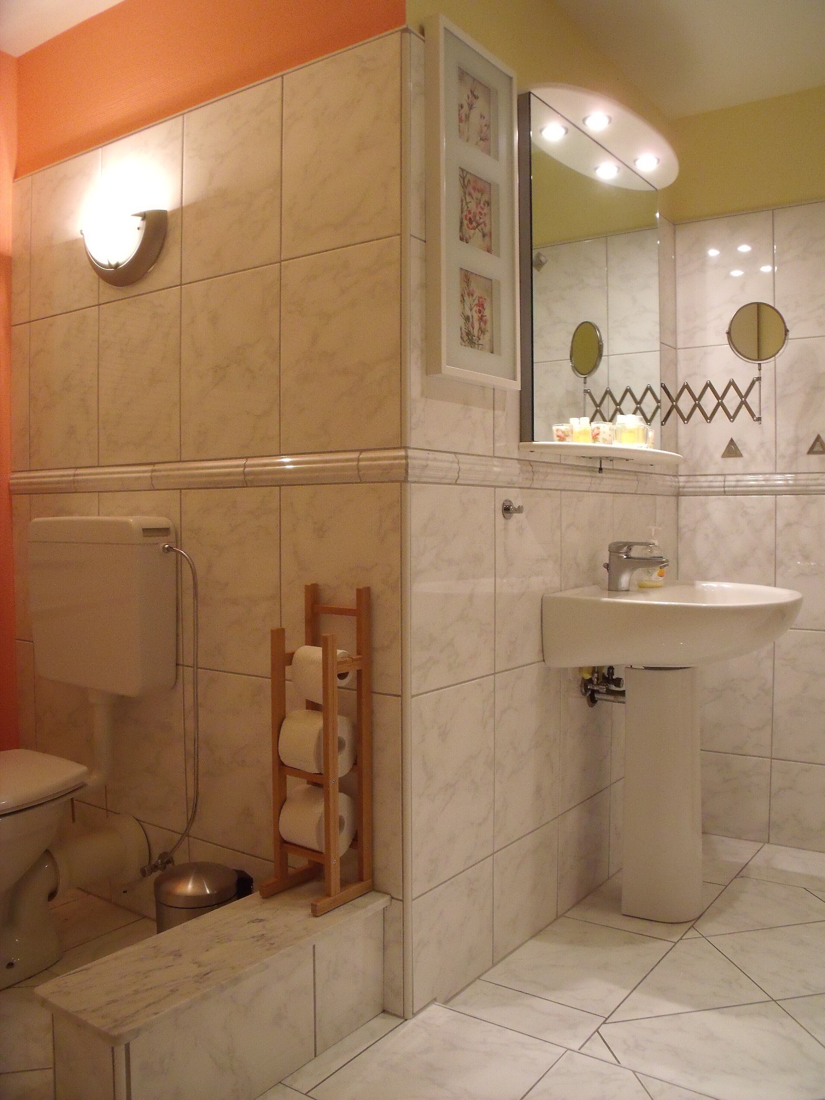 A bathroom with a toilet, a sink, a shower, and a towel rack.