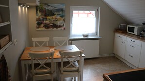 A kitchen with a dining table, chairs, a microwave, and a window with a view. - Apartment 'Ferienwohnung Mandelblüte' with Mountain View and Wi-Fi (Schotten)