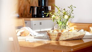 Eine Küchenarbeitsplatte mit einem Korbwägelchen, das Brot, eine Blumenvase und eine Kaffeemaschine im Hintergrund enthält.