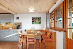 A cozy kitchen with wooden cabinets, a dining table, and a bench.