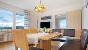 Zona pranzo moderna con tavolo in legno, sedie e lampadario.