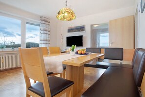 Un espace repas moderne avec une table en bois, des chaises et un luminaire suspendu.