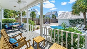Eine überdachte Terrasse im Freien mit Holzmöbeln, einem Pool und Blick auf angrenzende Häuser.