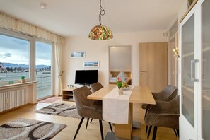 Un espace de salle à manger moderne avec une table en bois, des chaises marron, un luminaire décoratif suspendu et une vue dégagée grâce à de grandes fenêtres.