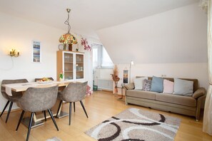 A dining area with a table, chairs, and a chandelier. There is a sofa and a window in the background. - Apartment 3 Marschall with Shared Garden, Balcony and Wi-Fi (Wasserburg)