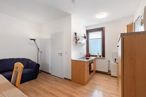 Un espace de vie compact comprenant un coin cuisine, un canapé, une table à manger et une chaise.