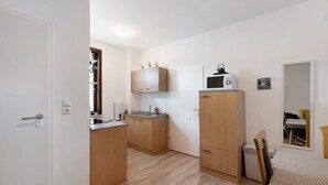 A compact kitchen with wooden cabinets, a microwave, and a small sink. - Apartment '1 Obergeschoss' with Shared Terrace, Shared Garden and Wi-Fi (Ilsenburg (Harz))