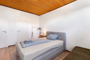 Une chambre à coucher comprenant un lit, une table de chevet, une lampe et une armoire.