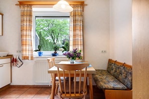 A compact kitchen with a dining table, wooden chairs, a bench, and a window with curtains. - Holiday Home 'Monteurwohnung' with Private Terrace and Wi-Fi (Schwanewede)