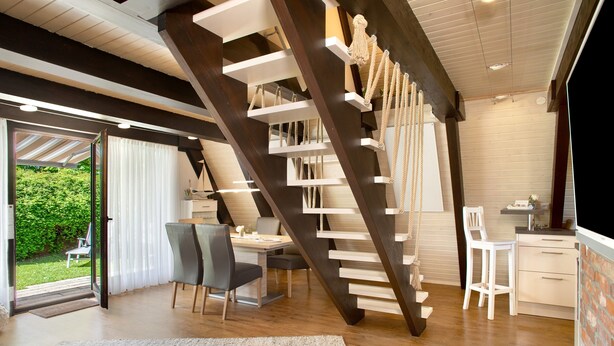 Un interior moderno con una escalera de madera, un comedor y una cocina.