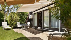 Un patio con mobiliario exterior, un área cubierta y un ventanal corredera que da a una casa moderna.