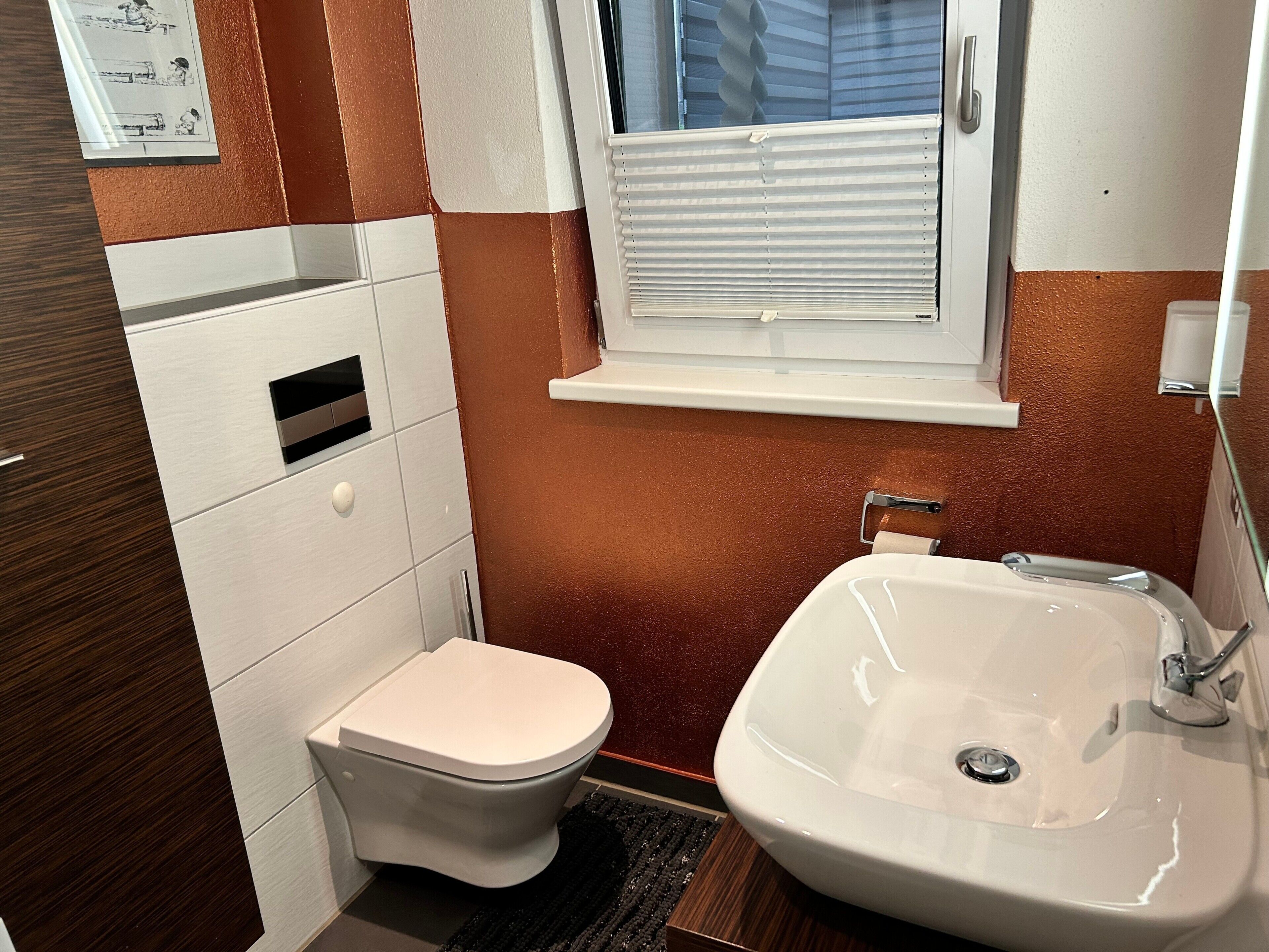 Ein Badezimmer mit Toilette, Waschbecken, Fenster und Handtuchhalter.