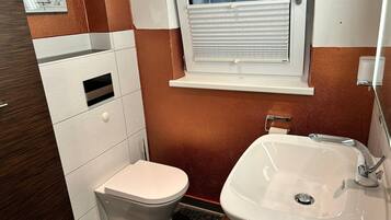 Ein Badezimmer mit Toilette, Waschbecken, Fenster und Handtuchhalter.