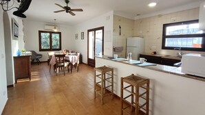 A kitchen with a dining area, wooden flooring, a ceiling fan, and a window providing natural light. - House with pool near the beach of Riells. HUTG-073666 (l'Escala)
