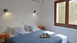 A bedroom with a bed, bedside tables, an air conditioner, wall-mounted lights, and a window with a view of greenery. - House with pool near the beach of Riells. HUTG-073666 (l'Escala)
