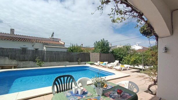 A poolside dining area with a table set for two, a pool, and a view of the surrounding neighborhood. - House with pool near the beach of Riells. HUTG-073666 (l'Escala)