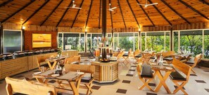 A spacious indoor dining area with wooden furniture and a central bar. - Justa Lazy Haven Corbett, Uttarakhand (Ramnagar)