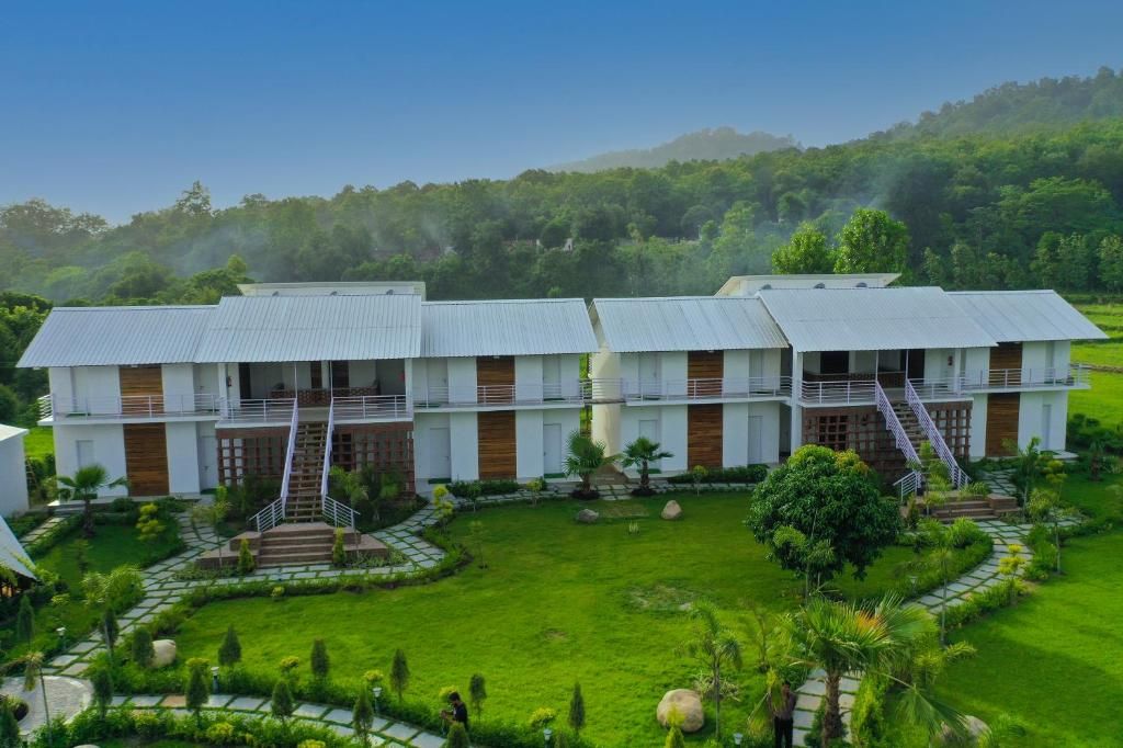 A modern hotel with a symmetrical design, featuring a central courtyard with a well-maintained lawn and pathways.