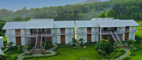 A modern hotel with a symmetrical design, featuring a central courtyard with a well-maintained lawn and pathways.