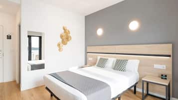 A modern hotel room with a large bed, bedside tables, a mirror, and decorative wall art.