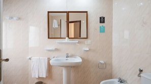 Une salle de bain équipée d’un lavabo, d’un miroir, d’un porte-serviettes et de toilettes.